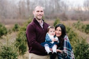 A family photo session with a family of three at a Christmas Tree Farm in Alto Michigan at Postema Christmas Tree Farm.