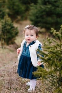 A family photo session with a family of three at a Christmas Tree Farm in Alto Michigan at Postema Christmas Tree Farm.