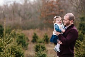 A family photo session with a family of three at a Christmas Tree Farm in Alto Michigan at Postema Christmas Tree Farm.