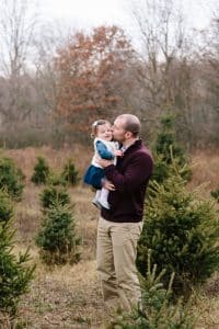 A family photo session with a family of three at a Christmas Tree Farm in Alto Michigan at Postema Christmas Tree Farm.