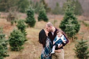 A family photo session with a family of three at a Christmas Tree Farm in Alto Michigan at Postema Christmas Tree Farm.