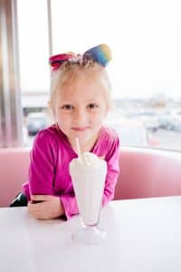 A Grand Rapids kids photoshoot in a pink diner with a milkshake.