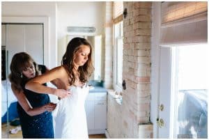 Photograph of Bride's mother helping her daughter into her wedding dress