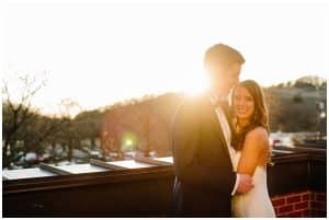 Bride and groom standing with the sun peaking through and trees in the background