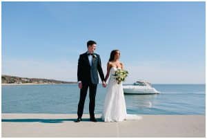 Wedding photo of couple standing on Grand Haven beach with water and a boat in the background