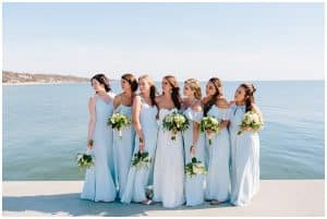Bridal party standing in front of the Grand Haven beach with the shoreline in the background.