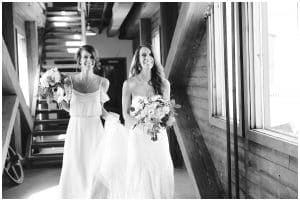 Black and white photograph of maid of honor walking bride to the entrance of her wedding at the Harbourfront Place in Grand Haven