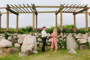 Outdoor Engagement photography session at Cherry Point Farms where couple is laughing and holding hands under a wooden archway