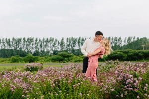 Cherry Point Farms engagement photography session in a flowery field where couple is kissing under the blue sky