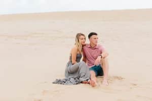 Couple sitting and looking off in the distance for their engagement photos at Silver Lake Sand Dunes
