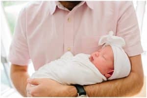 Baby girl is held in her fathers arms during newborn photography session
