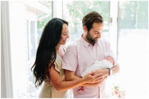both mother and father look lovingly at their newborn daughter during their in home photography session