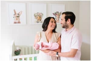 Mother and father smiling at each other in the nursery of their newborn baby girl. Baby girl is being cradled in her mother's arms