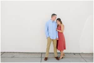 Couple standing in front of a clean white wall in Grand Rapids, Michigan for their engagement photos.