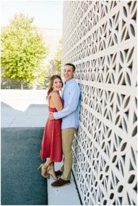 Couple holding each other close while standing in front of an intricate wall in Grand Rapids.