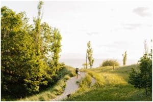 Vast scenery at Kirk Park with an engaged couple in the foreground walking into the sun.