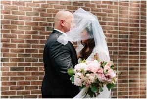 The Bride shares a special moment with her father outside near a brick wall right before the wedding ceremony.