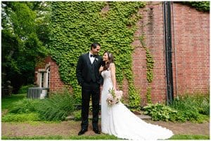 The bride and groom stand next to each other and look up to each other and smile.