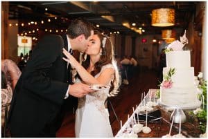 The bride and groom share a kiss right after they cut the cake at their reception.