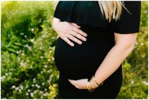 A close up image of a mother holding her baby bump with both hands as she anxiously waits for her new baby.