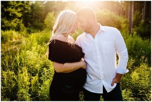 A couple leans in close and gazes into each others eyes under the sun at Holland State Park for their maternity photos.