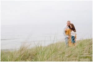 An engaged couple at Tunnel Park choose to stop in the tall grass and rest on each other for their engagement photos.
