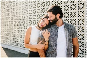 A young couple standing and posing in front of a pretty and unique white wall in downtown Grand Rapids for a lifestyle photo shoot.
