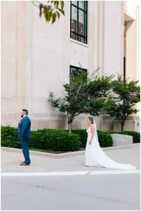 A bride and groom stand outside and prepare for the first look.