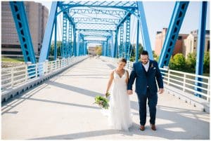 A recently married couple walks the blue bridge in Grand Rapids while holding hands