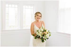 A bride smiles and holds her flowers.