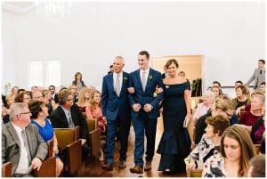 A groom walks family down the aisle before his wedding ceremony begins.