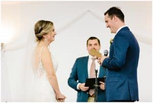 A bride and groom stand at the alter and smile while sharing vows with each other.