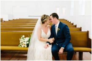A bride and groom sit on some benches in a chapel in Holly Michigan on their wedding day.
