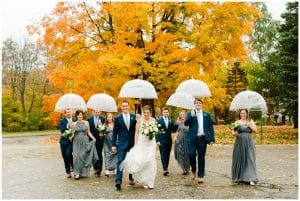 A bride and groom with their wedding party walking down a street with an orange tree standing in the background.