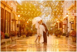 Couple standing under sparkling lights in the rain on their wedding day.