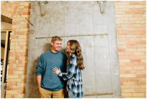 An engaged couple uses an old steel door as a backdrop to their engagement photos.
