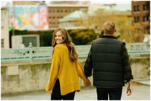 A young girl looks behind her as she smiles and holds the hand of her soon to be husband.