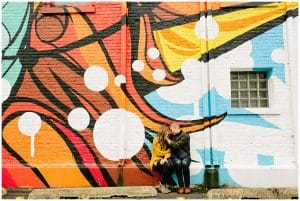 A fun mural is used as the backdrop for some fun engagement photos in the fall.