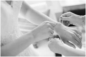 A bride receives help from her mother getting her jewelry on before her wedding.