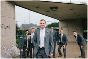 A groom posing for silly pictures with his groomsmen.