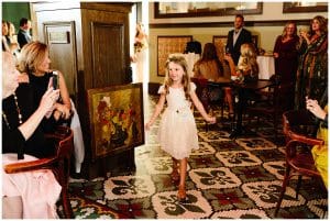 A flower girl walks through the guests and toward the groom.