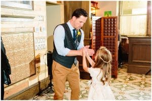 A groom and his flower girl share a special handshake before the wedding ceremony begins.