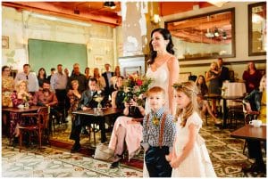 A bride stands at the alter with her two children.