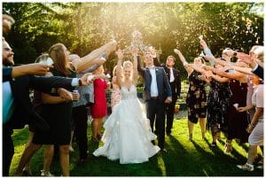 A couple celebrates with their guests outside during the summer with the sun shinning.