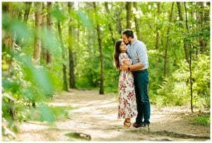 Engagement photo of a couple holding each other close in Proven Trails woods surrounded by green trees in the spring