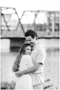 A soon to be bride hugs her fiance close as they stand in front of the Blue Bridge in Grand Rapids, Michigan.